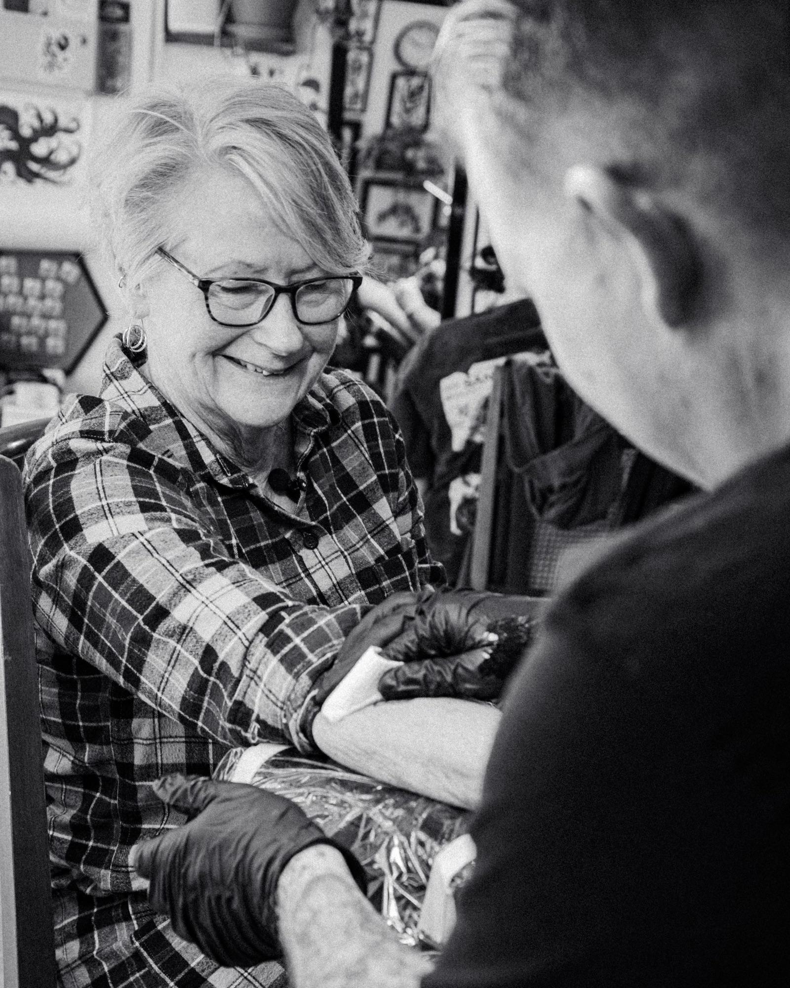 A client smiling while her forearm is tattooed