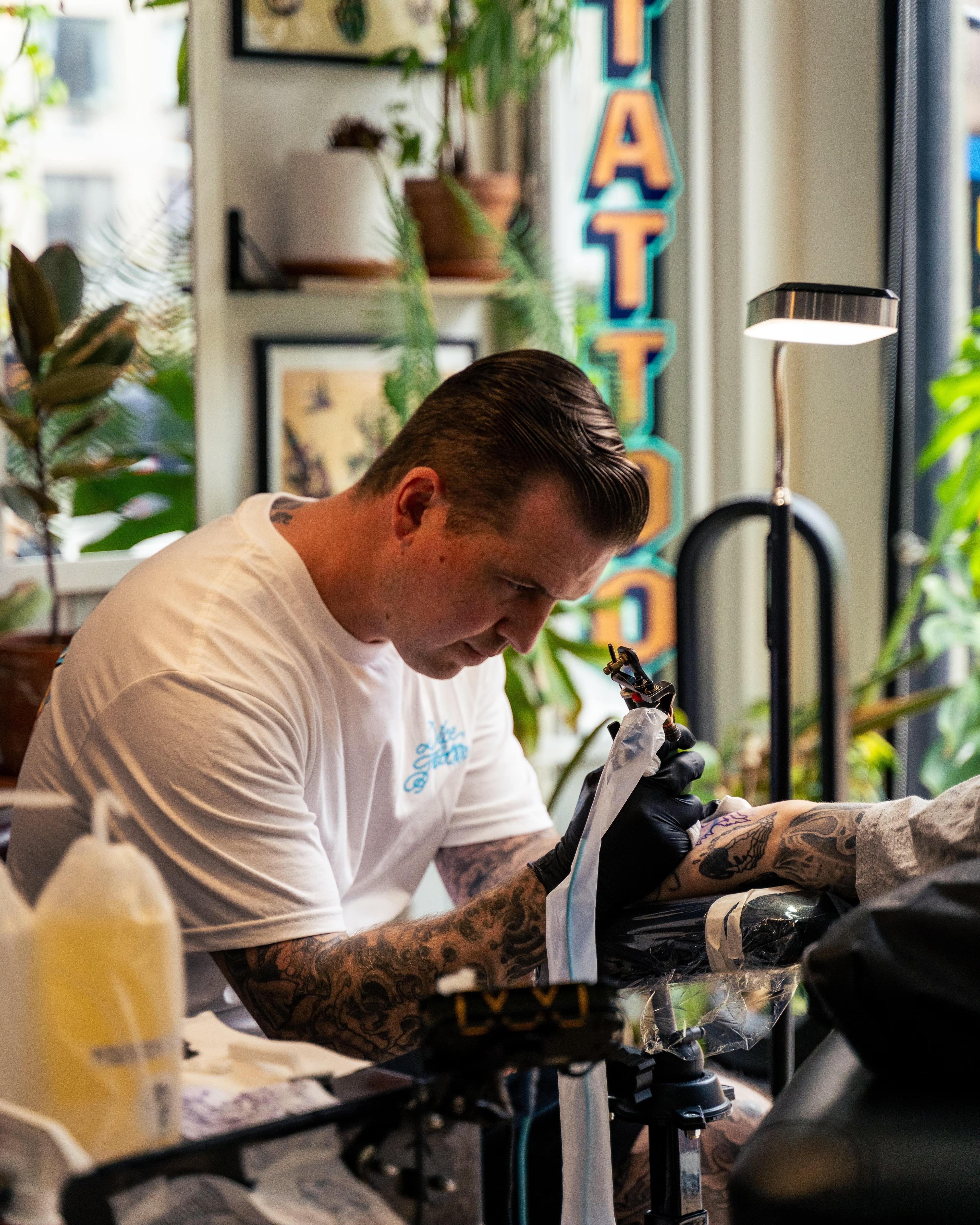 Mike Stapleton tattooing a forearm by the studio window